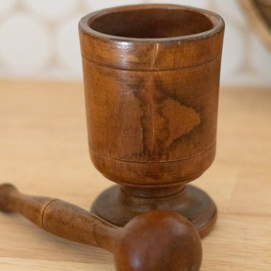 Wooden mortar and pestle on a wooden surface with a blurred background