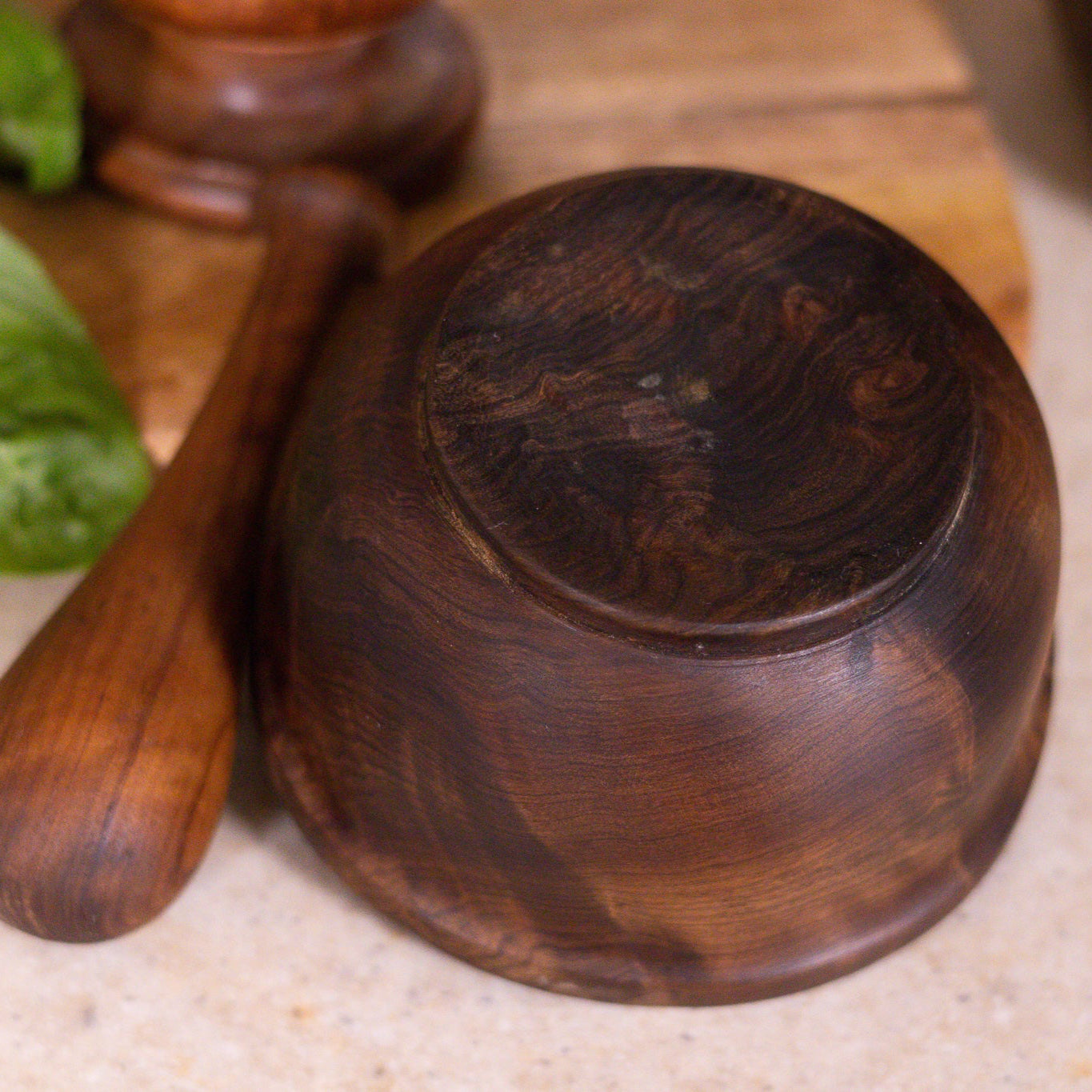 Wooden bowl and spoon on a textured surface with a blurred background