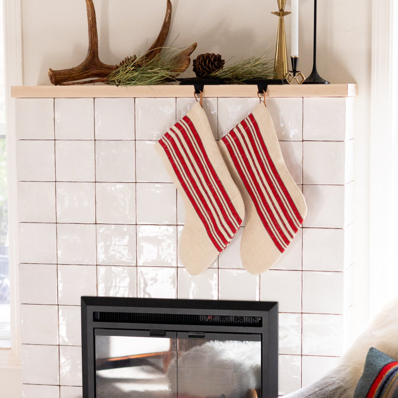Two red and white striped stockings hanging above a fireplace with a cozy living room setting.