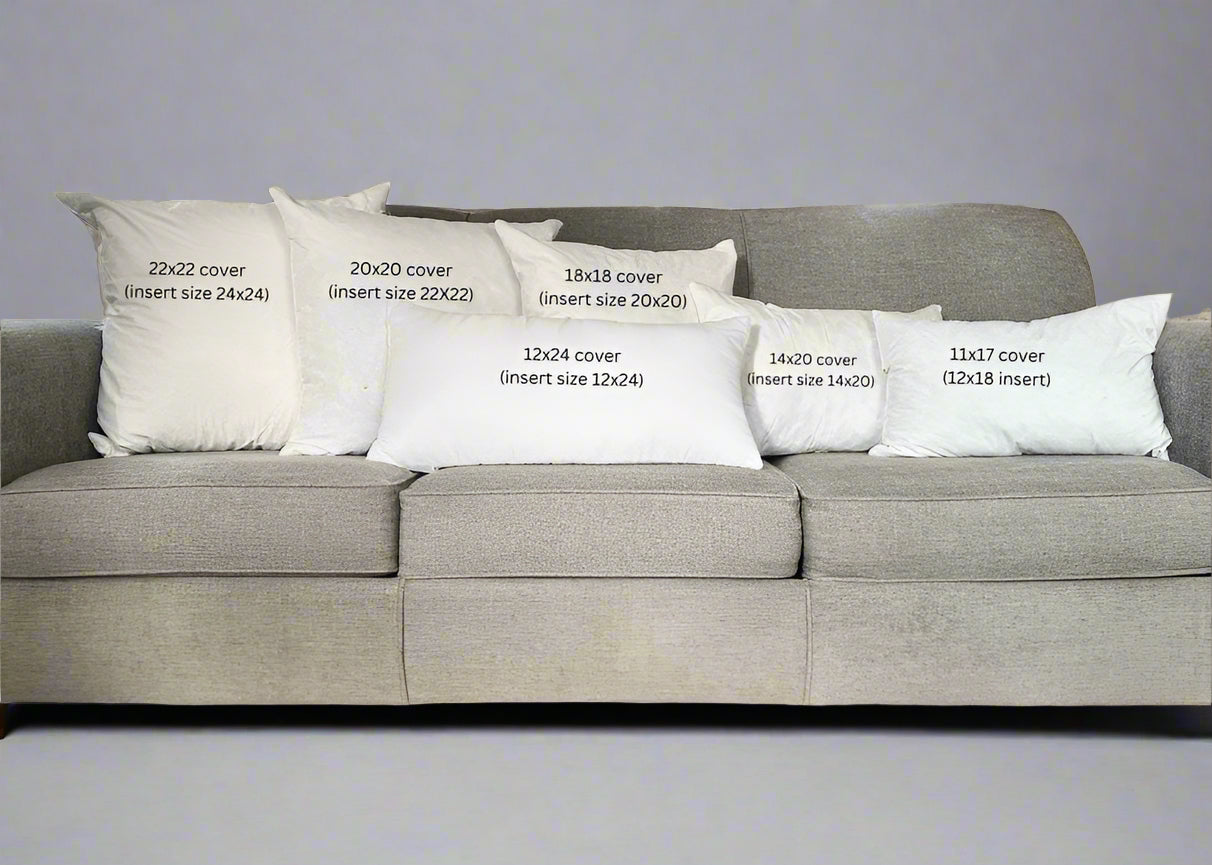 Gray sofa with decorative pillows displaying measurements in a living room.