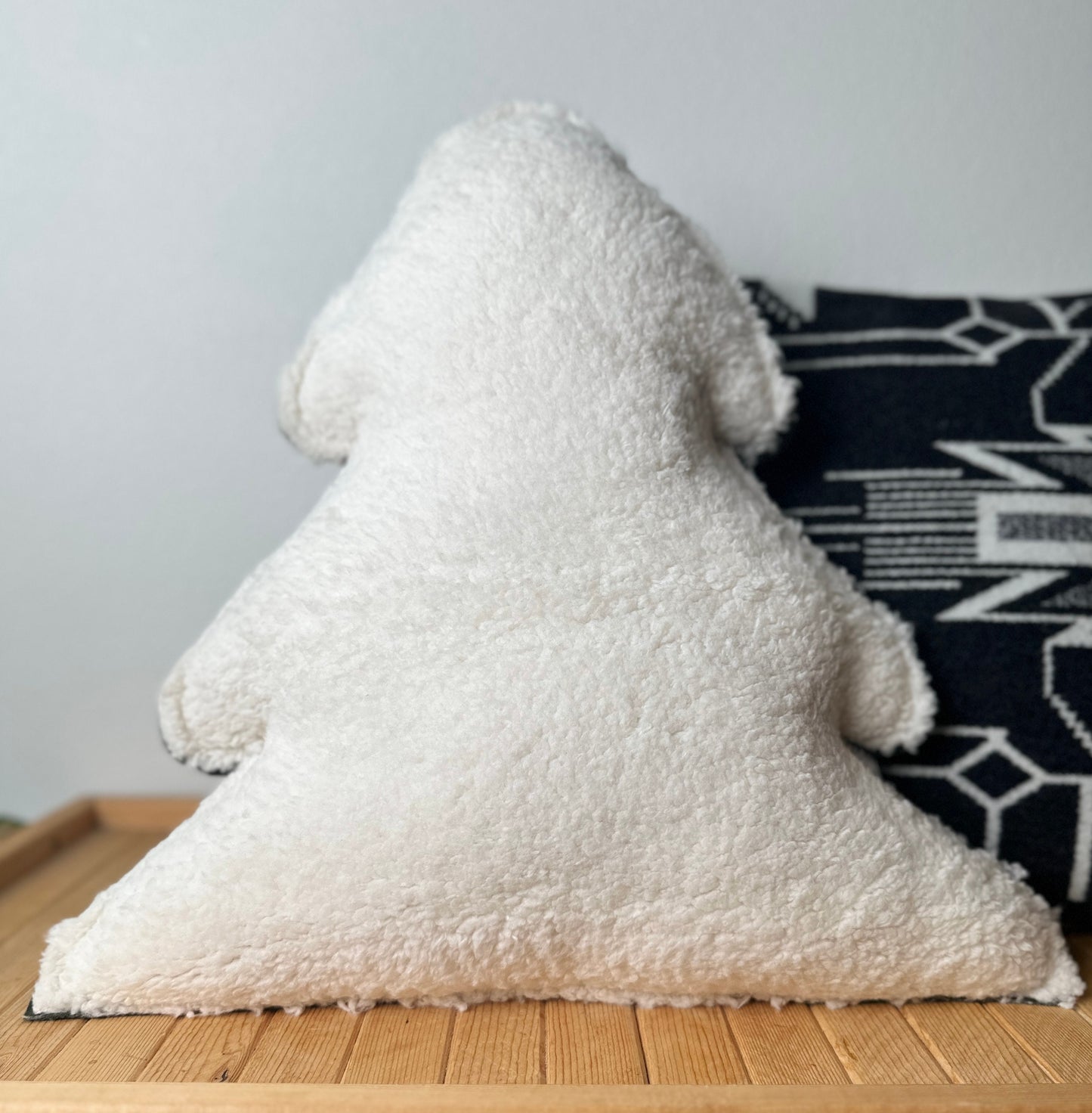 White textured pillow on a wooden surface with a gray wall in the background