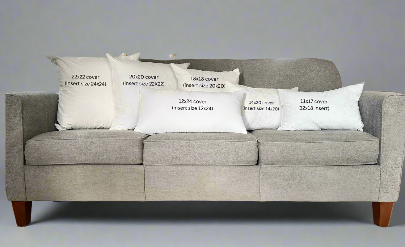 Gray sofa with decorative pillows displaying measurements in a living room setting.