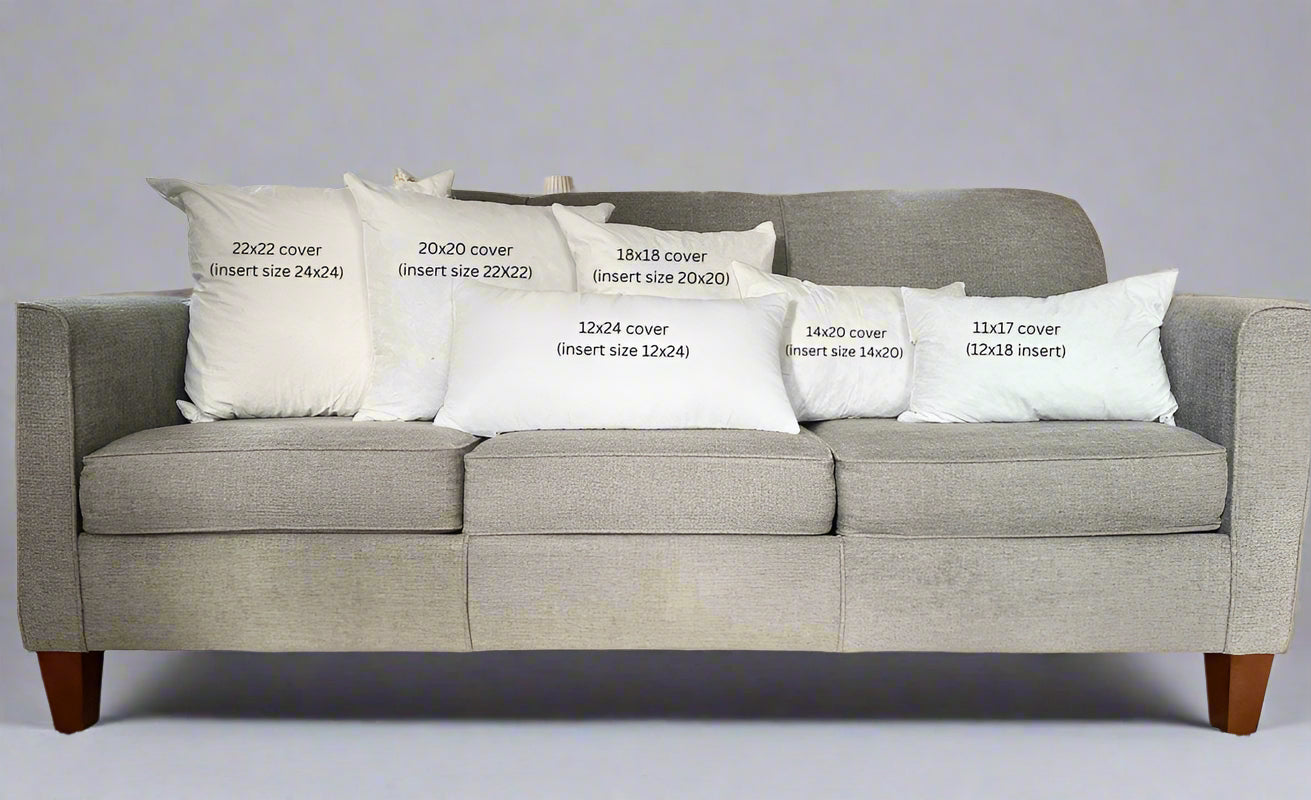 Gray sofa with decorative pillows displaying measurements in a living room setting.