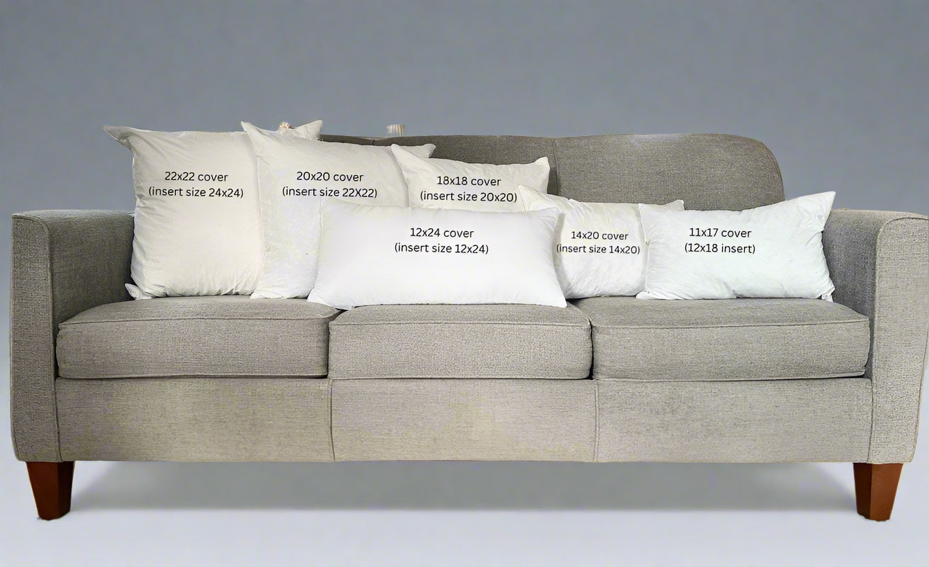 Gray sofa with decorative pillows displaying measurements in a living room setting.