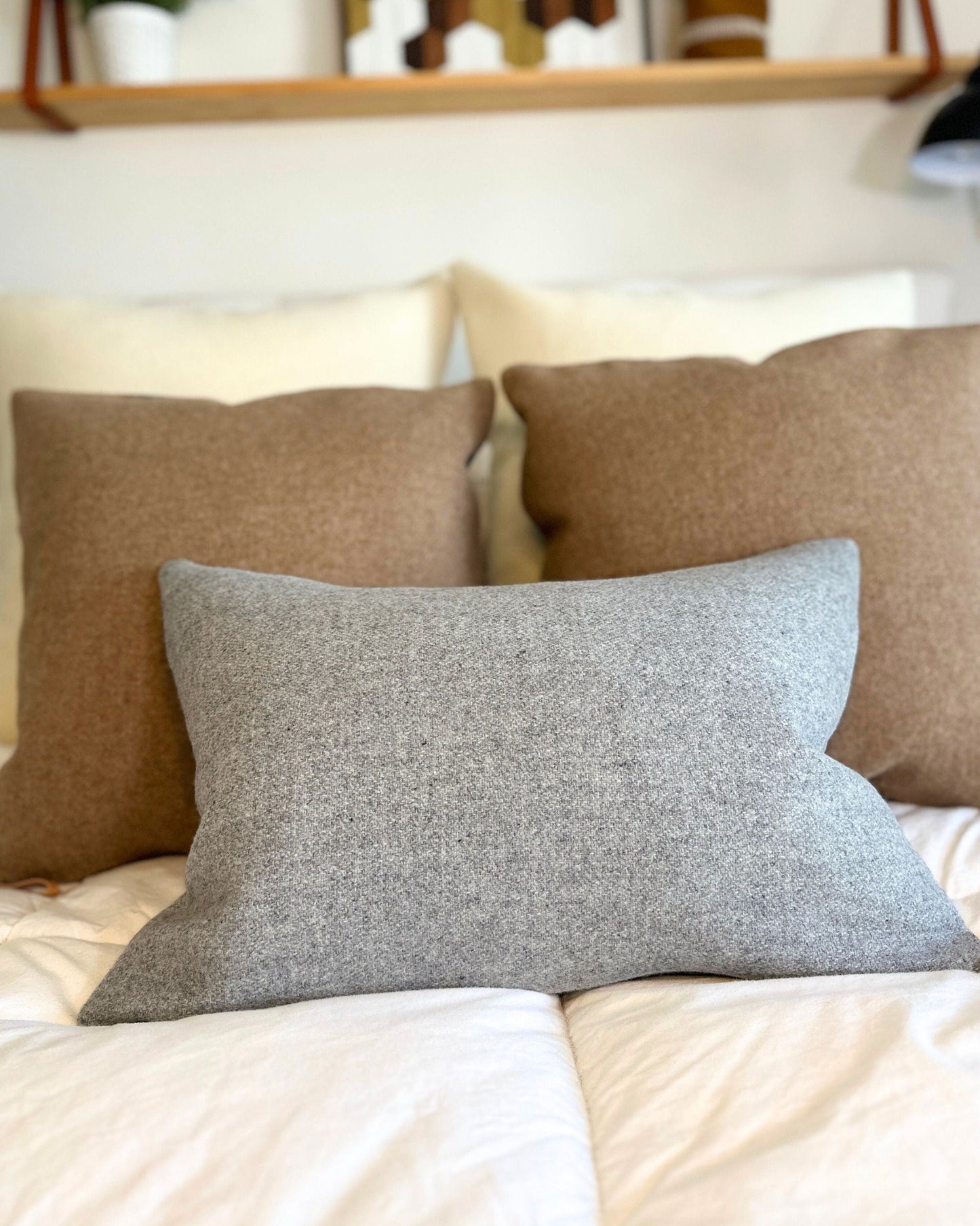 Three pillows on a bed with a neutral color scheme