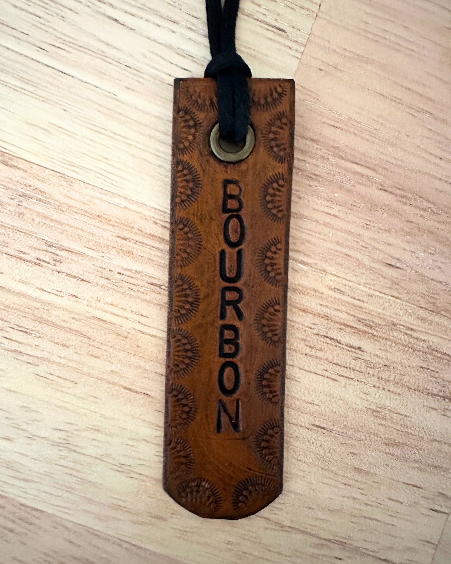 leather tag with 'Bourbon' engraving on a light wooden surface