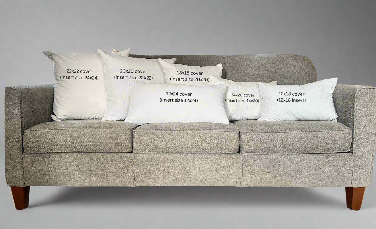 Gray sofa with decorative pillows and measurements printed on them in a living room setting.