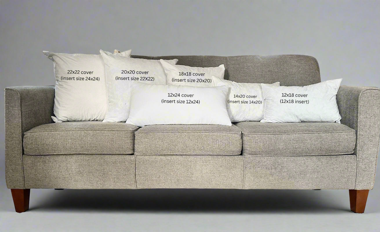 Gray sofa with decorative pillows labeled for size on a carpeted floor.