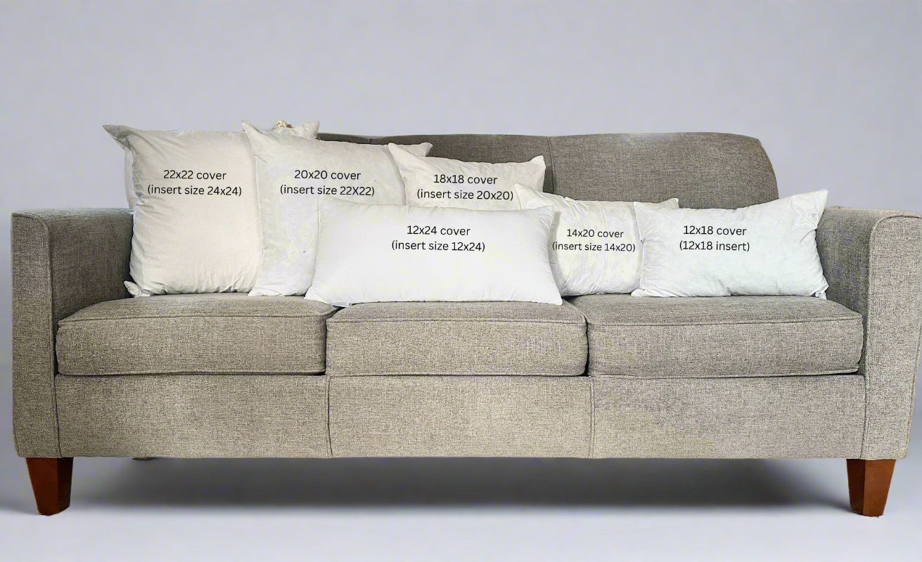 Gray sofa with decorative pillows and measurements printed on them in a living room setting.