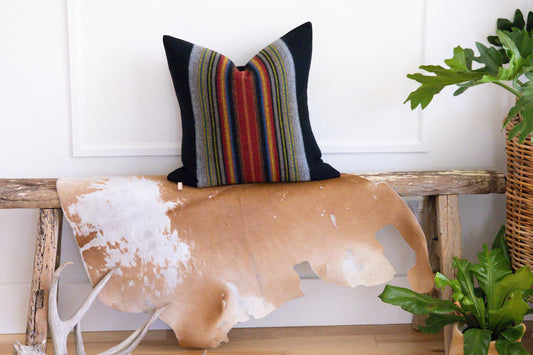 Decorative pillow with striped pattern on a cow-shaped cushion in a home setting.