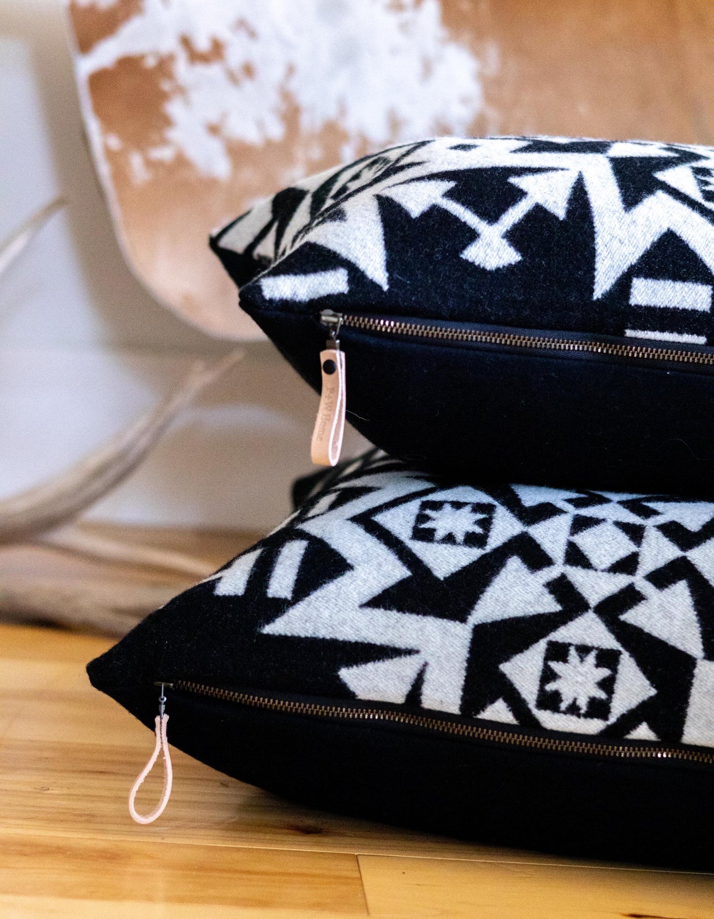 Two black and white patterned pouches with zippers on a wooden surface.