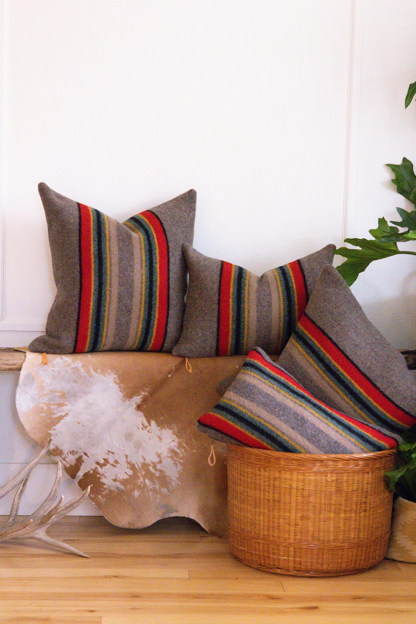 Decorative pillows with striped patterns on a wooden surface with a plant in the background