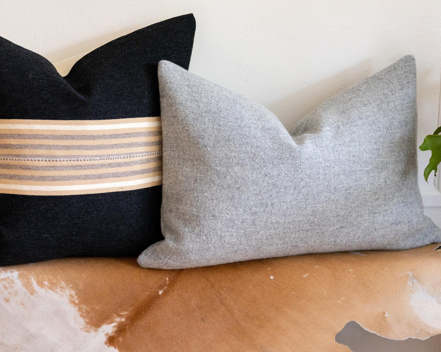 Two decorative pillows, one black with a striped pattern and one gray, on a textured surface.