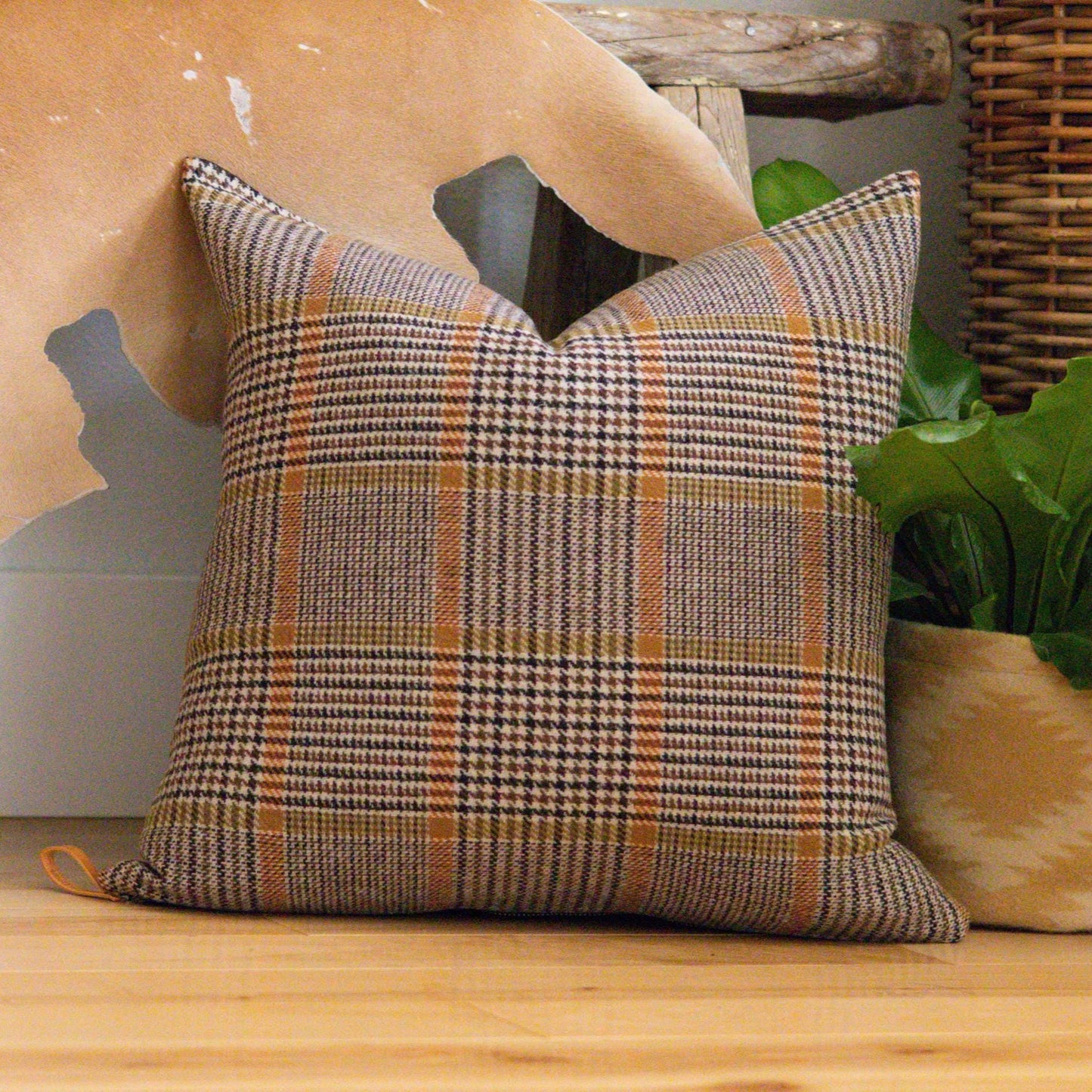Plaid pillow on a wooden surface with decorative elements in the background