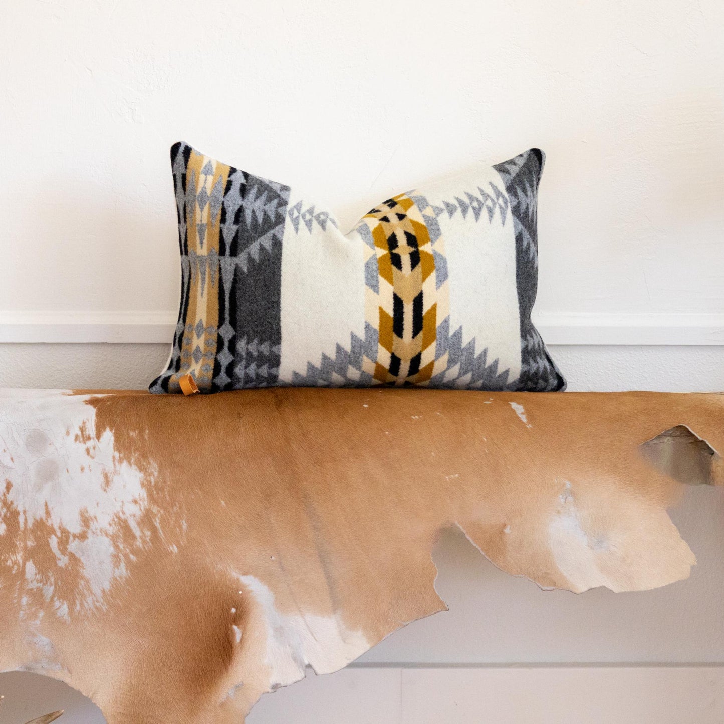 Decorative pillow on a wooden bench with a cowhide rug