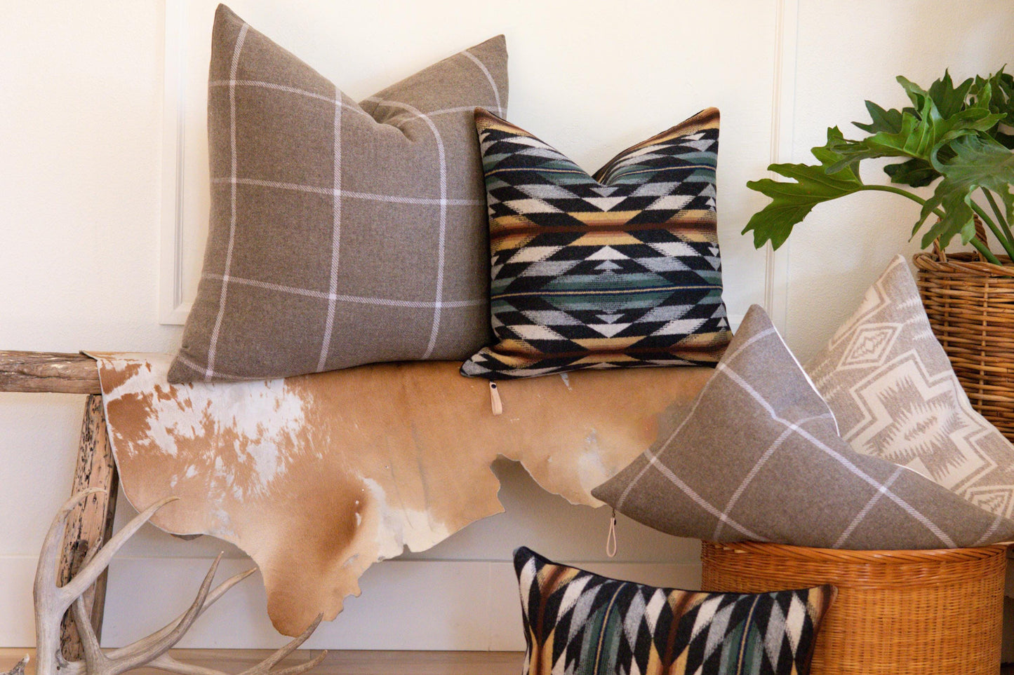 Decorative pillows on a bench with a cowhide rug and plant in the background