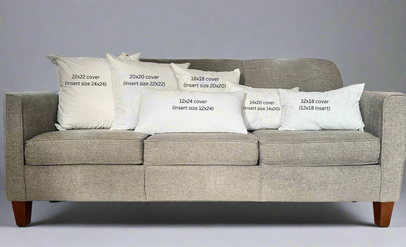Gray sofa with decorative pillows labeled for size on a carpeted floor.