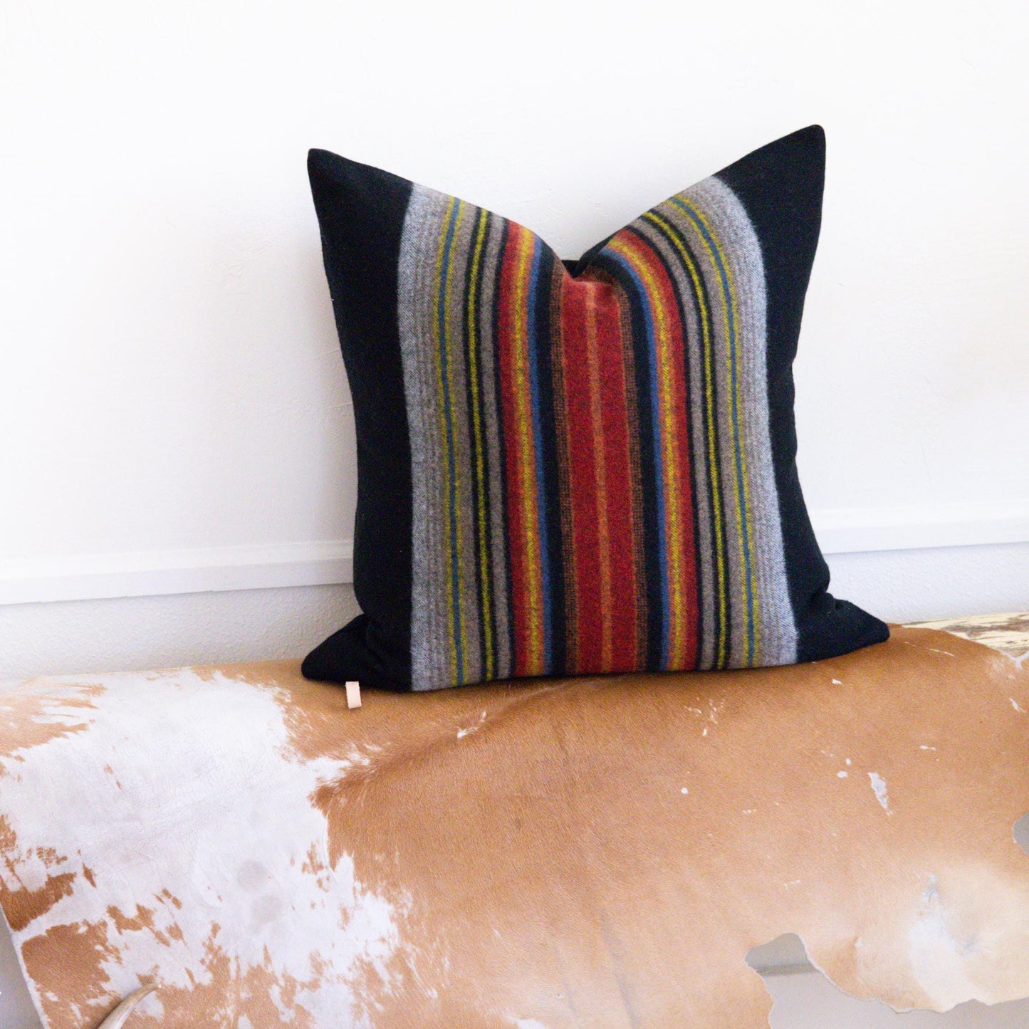 Decorative pillow with colorful stripes on a wooden surface