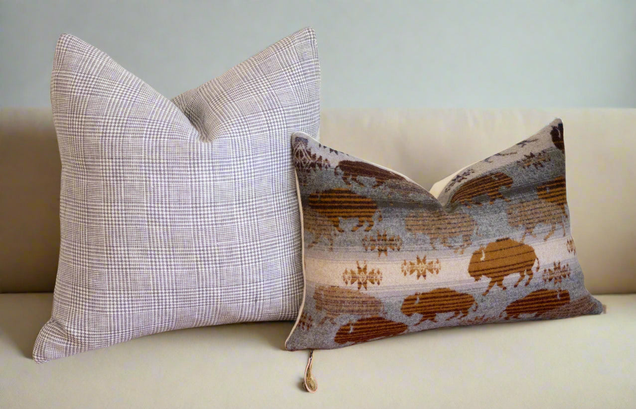 Two decorative pillows on a wooden surface with a neutral background