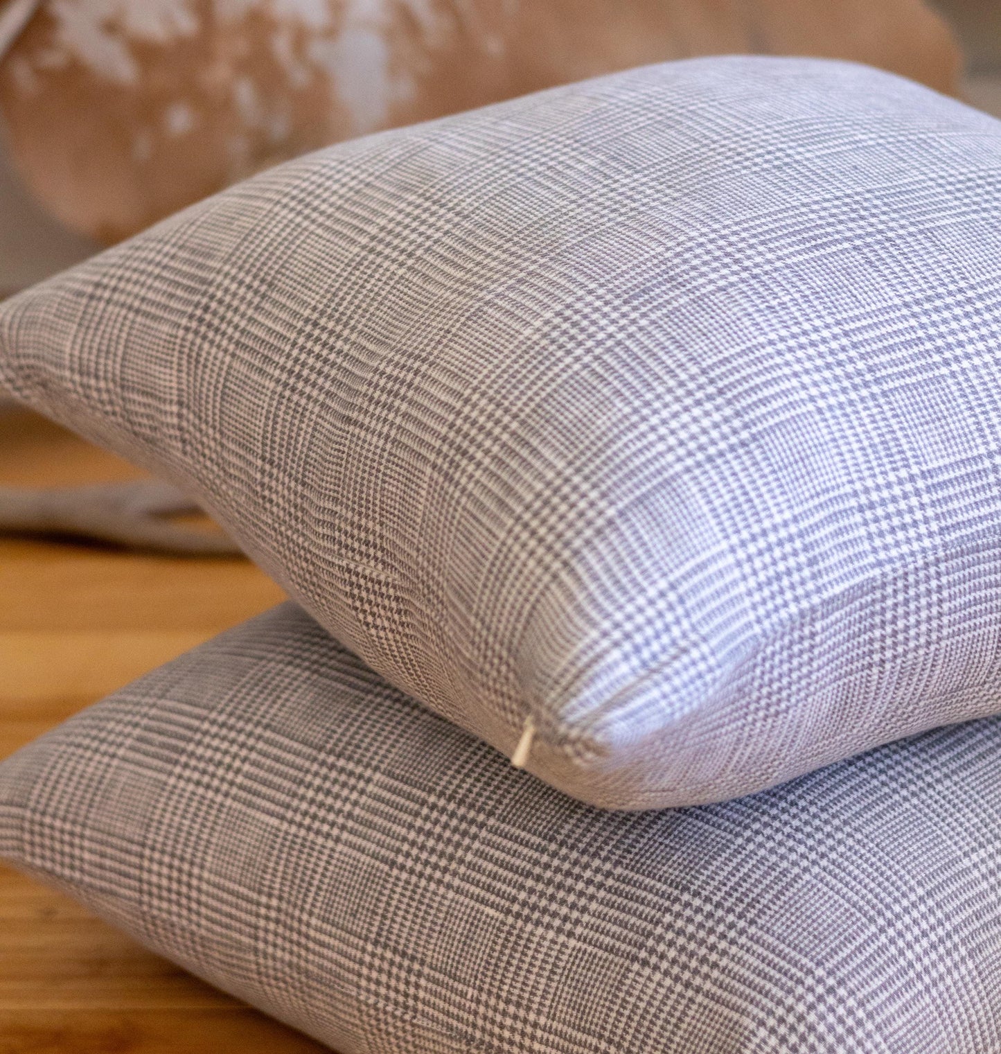 Two plaid-patterned pillows stacked on a wooden surface.