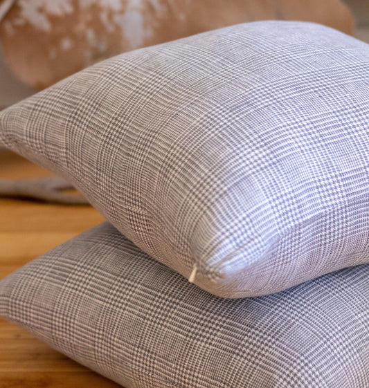 Two plaid-patterned pillows stacked on a wooden surface.