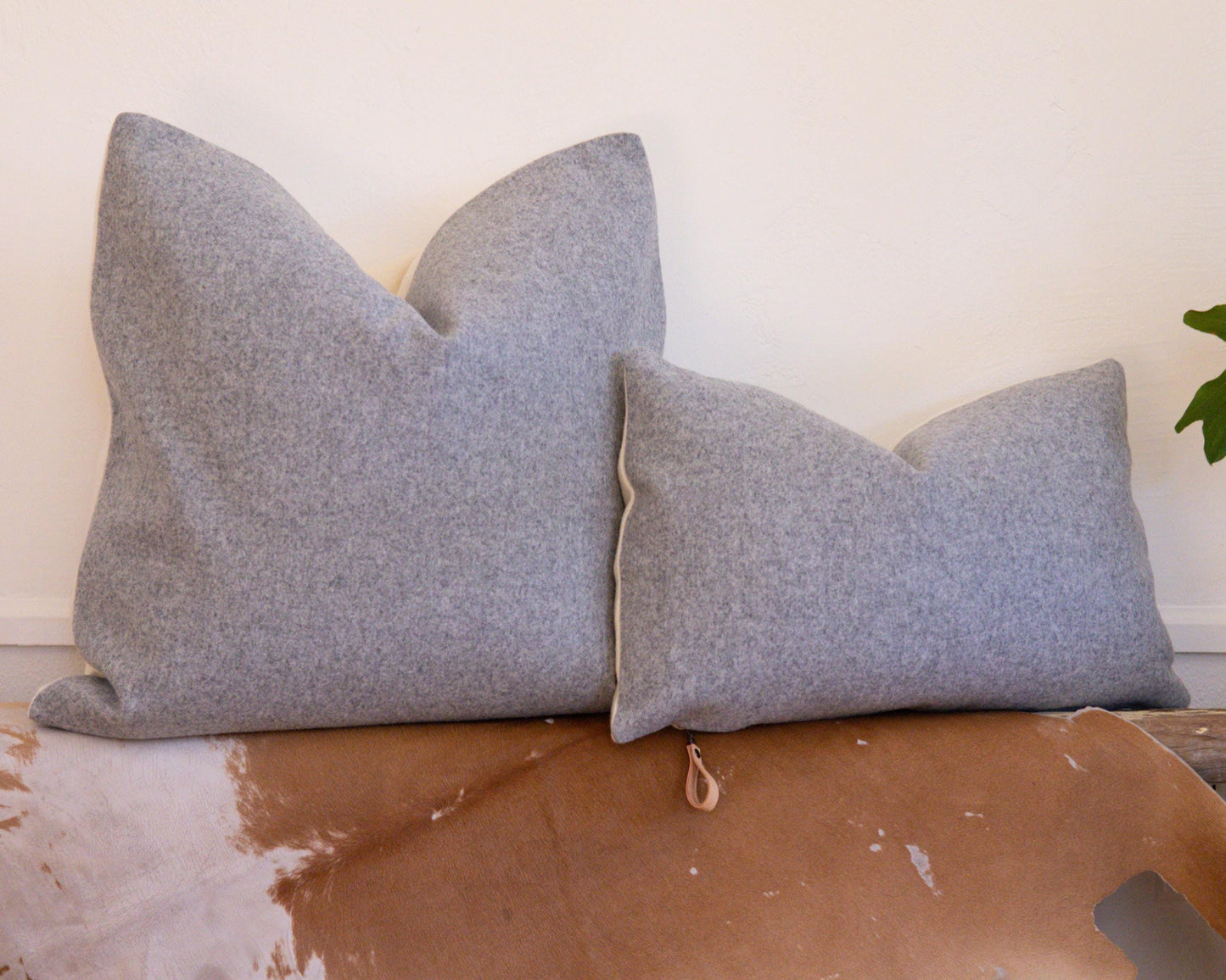 Two gray cushions on a wooden surface with a white wall in the background