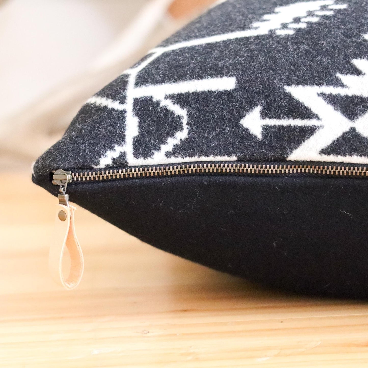 Black pillow with white geometric pattern on a wooden surface