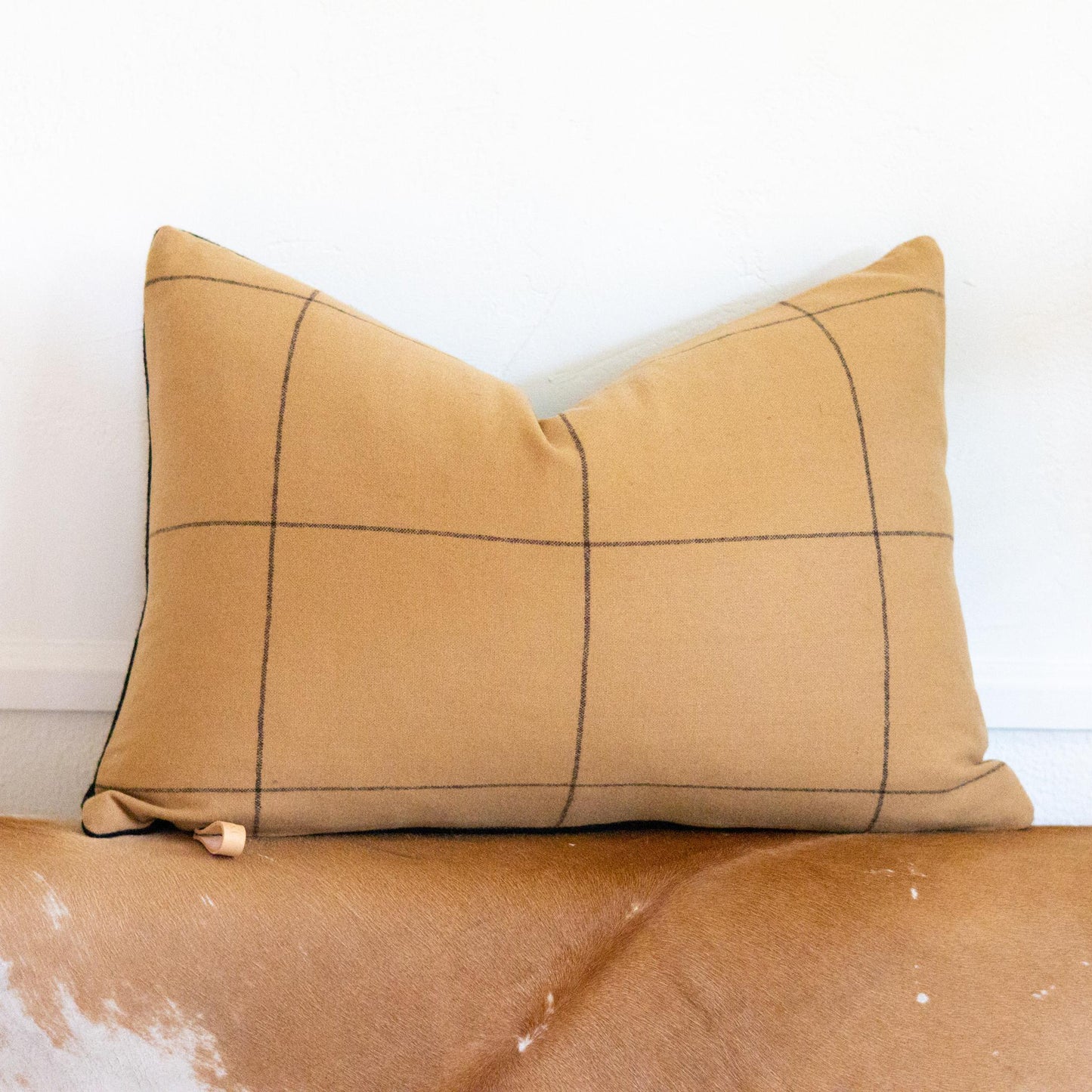 Beige pillow with black grid pattern on a beige surface