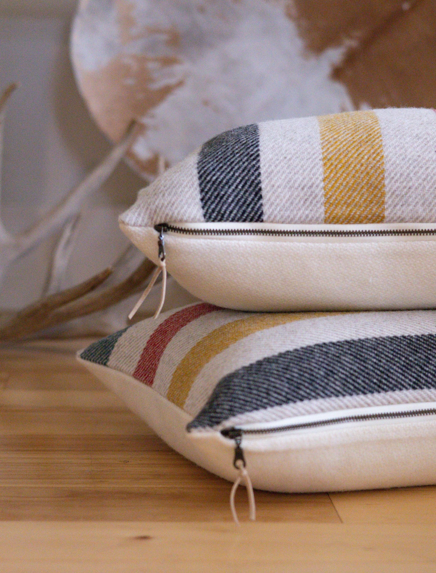 Two striped pillows with a zipper on a wooden surface