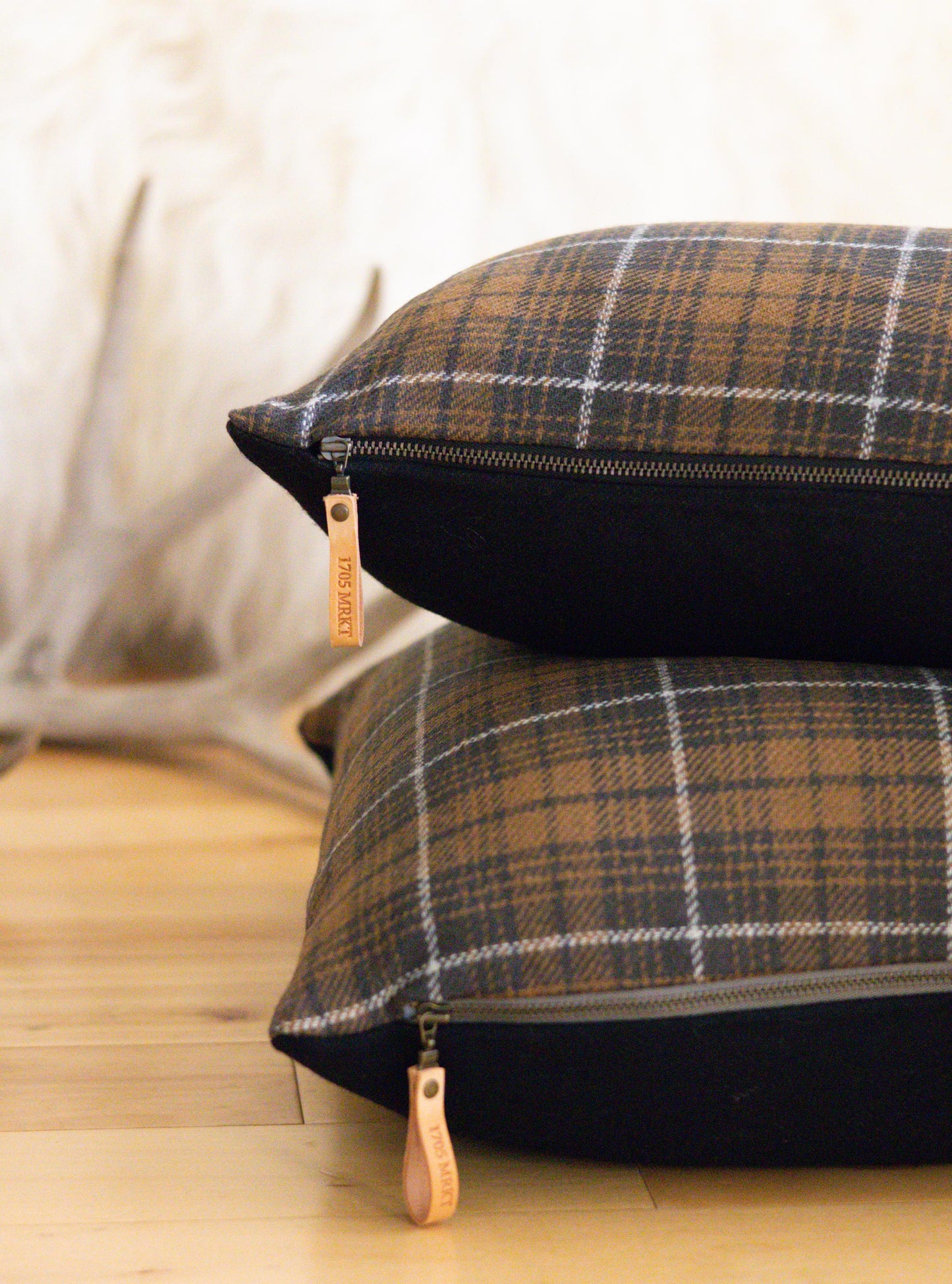 Plaid patterned cushions with zippers on a wooden floor.