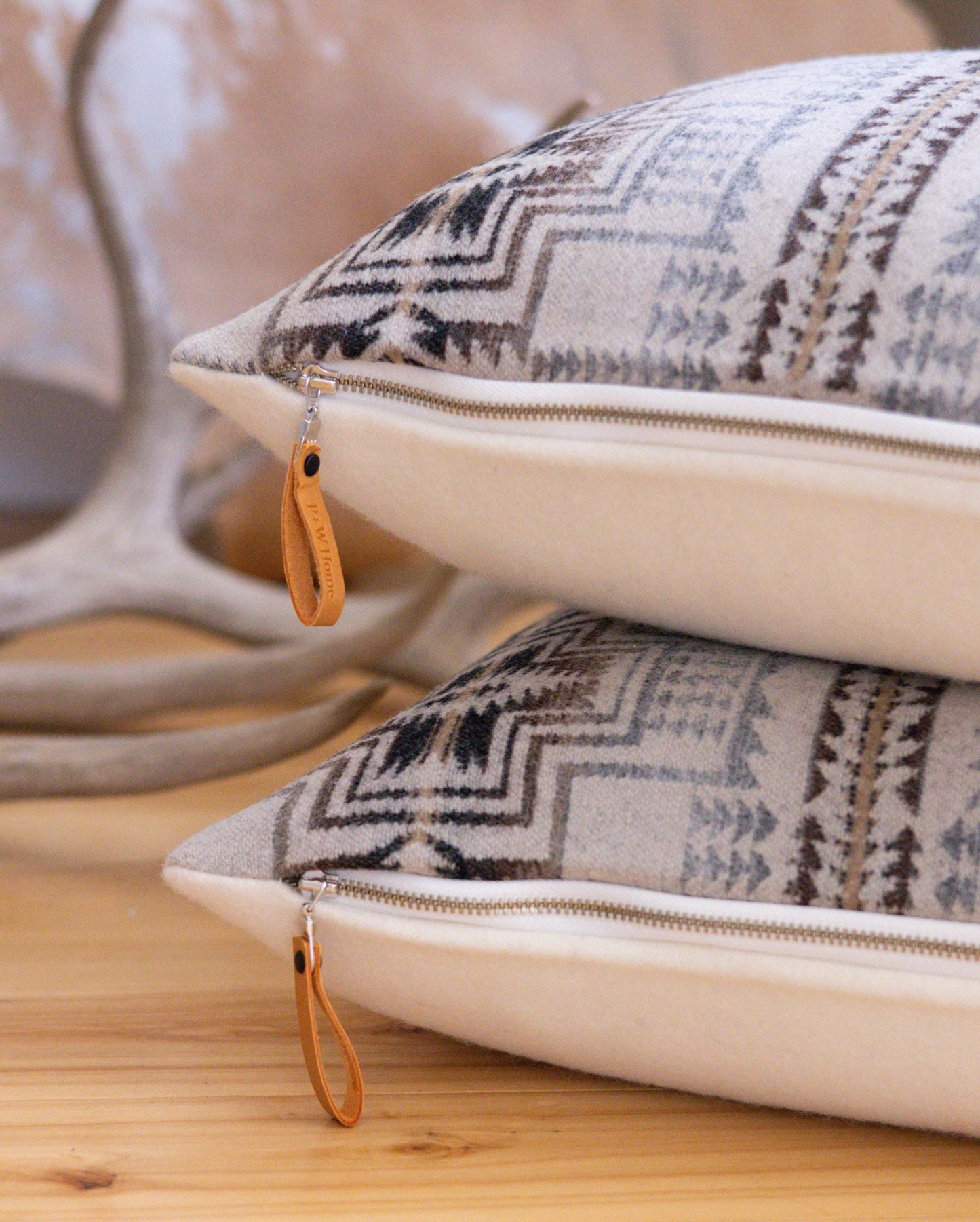 Two patterned pillows with zipper closures on a wooden surface.