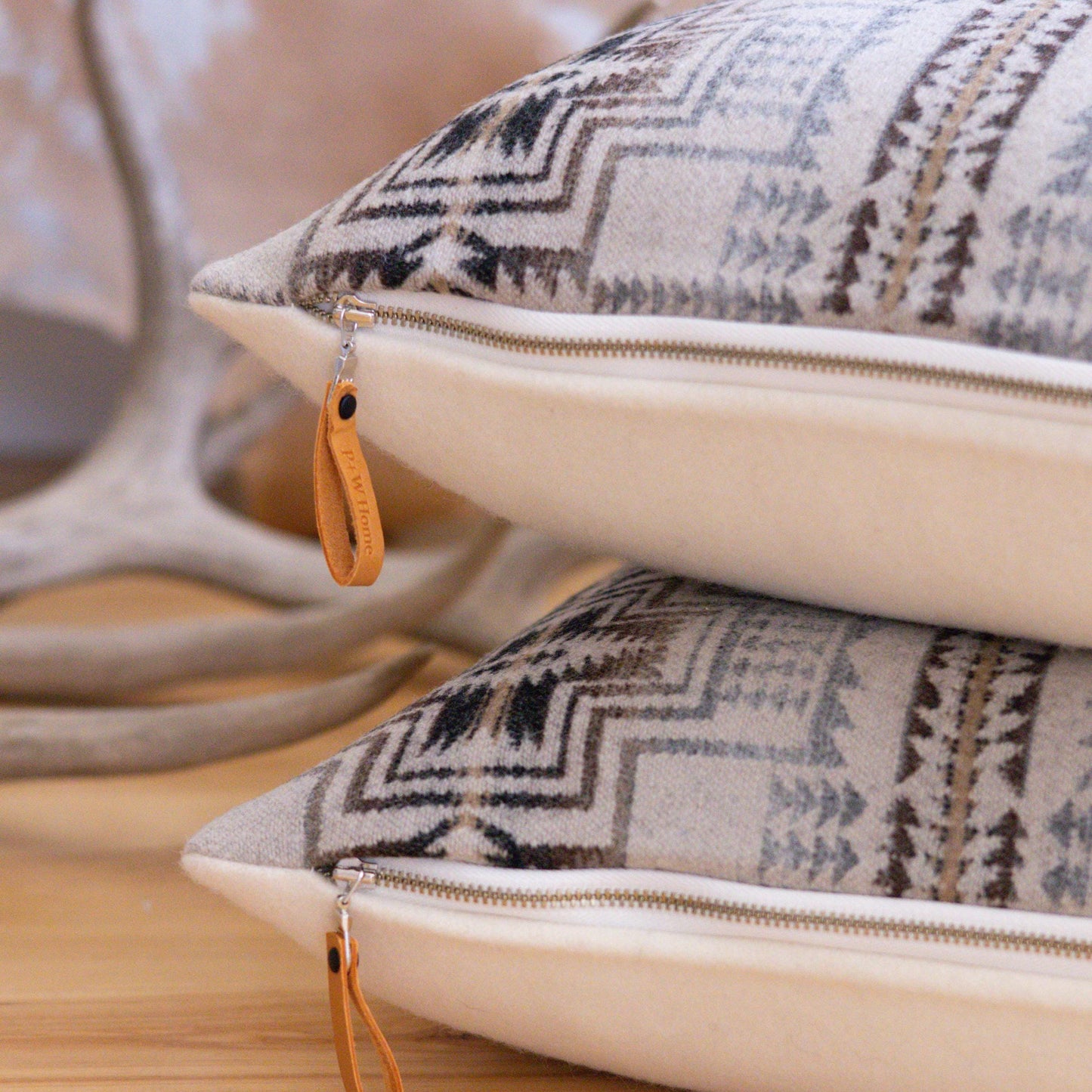 Two patterned Pendleton® pillows with zipper closures on a wooden surface.
