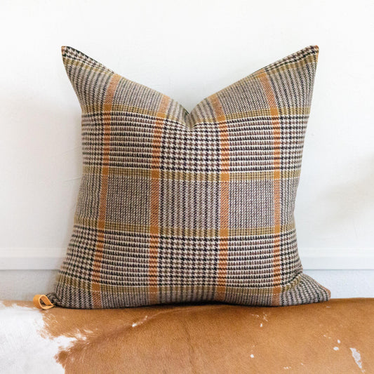 Plaid pillow on a brown surface with a white background
