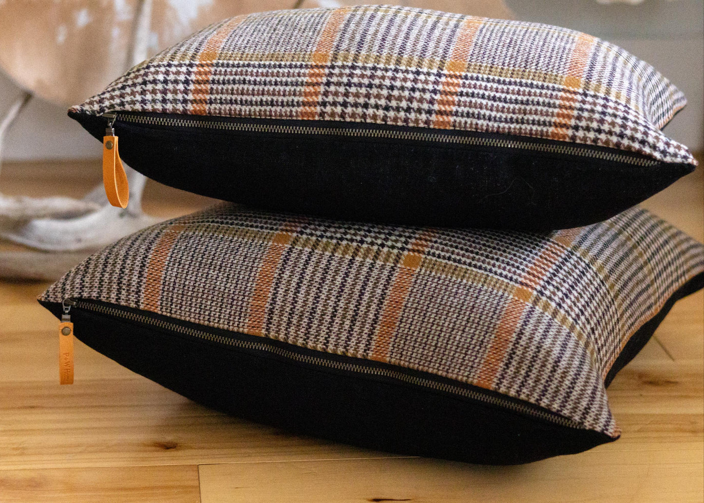 Two plaid cushions with black accents on a wooden floor.