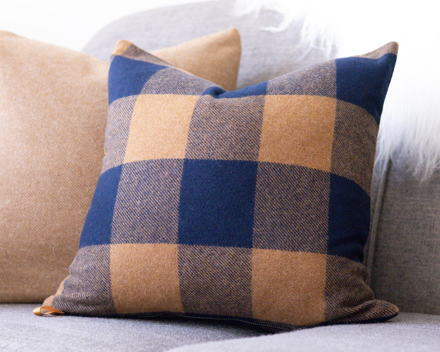 Plaid pillow on a sofa with a neutral background