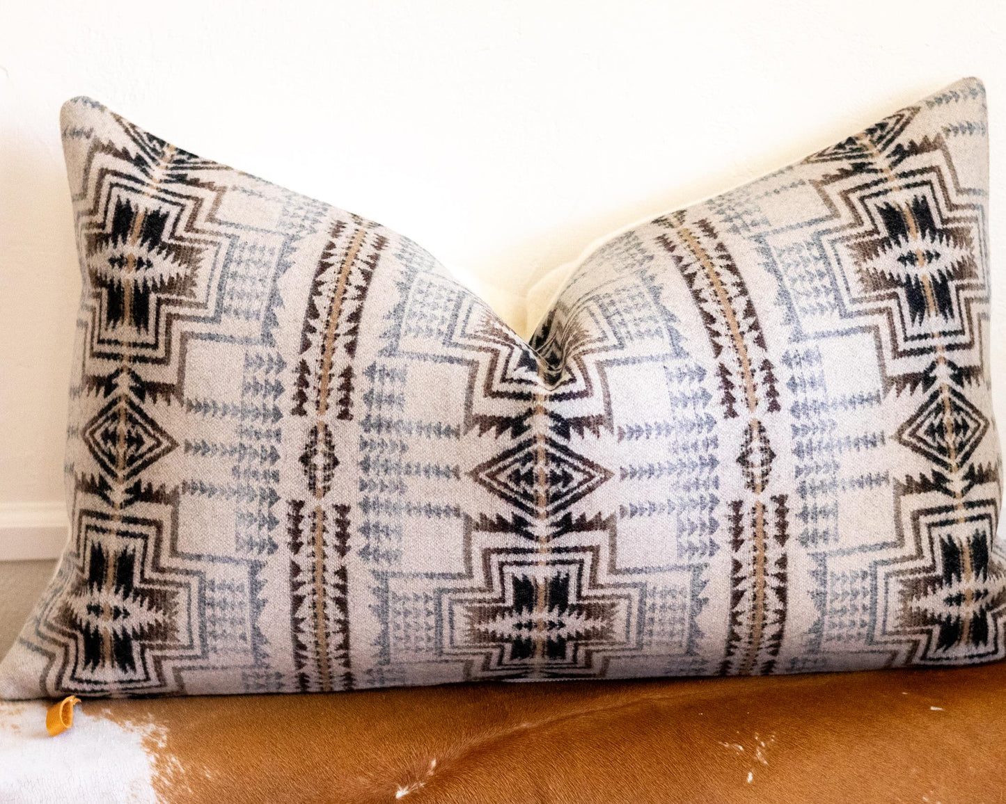 Decorative Pendleton® pillow with tribal pattern on a brown couch
