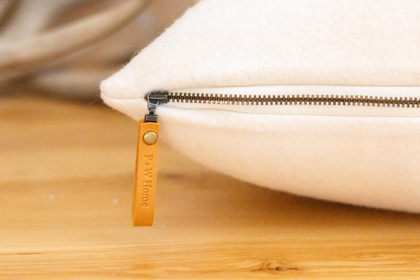 Close-up of a beige pouch with a zipper and visible brand name on a wooden surface