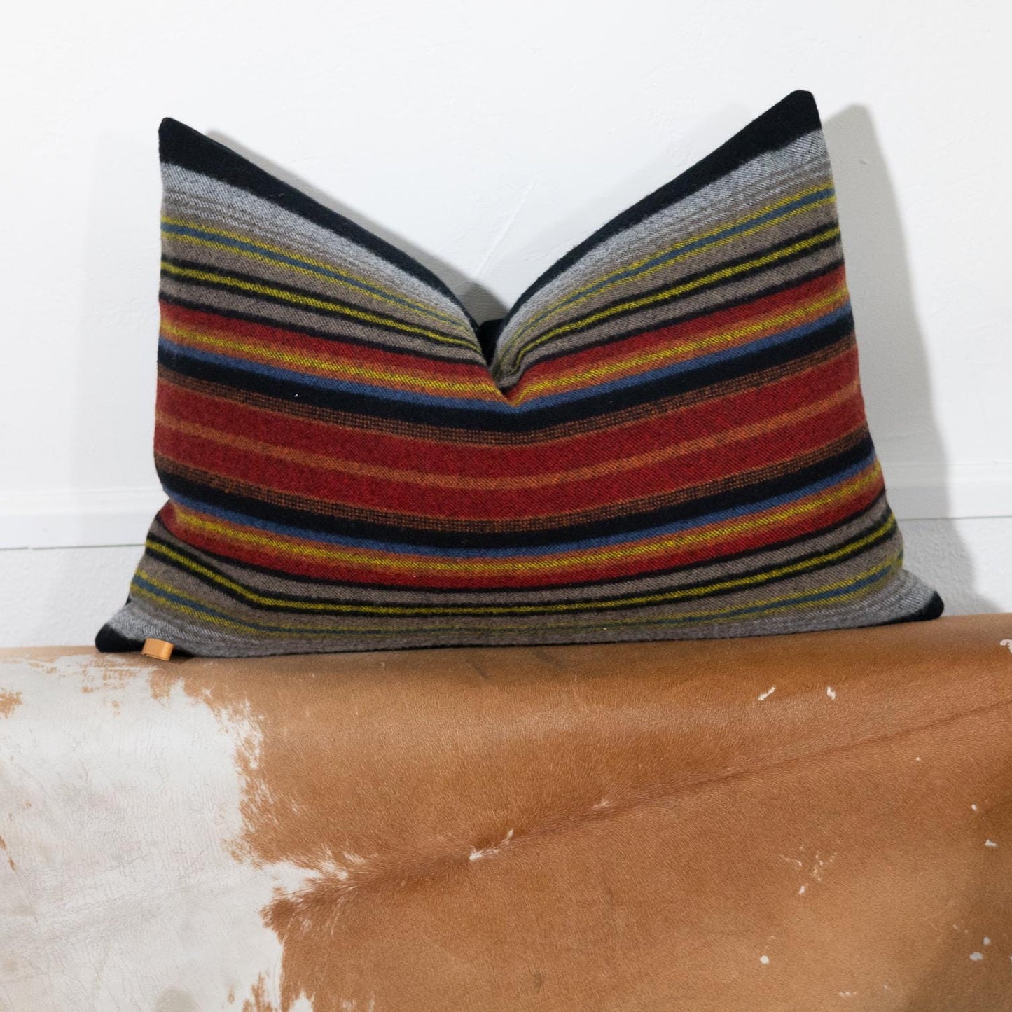 Striped pillow on a brown leather surface with a white background