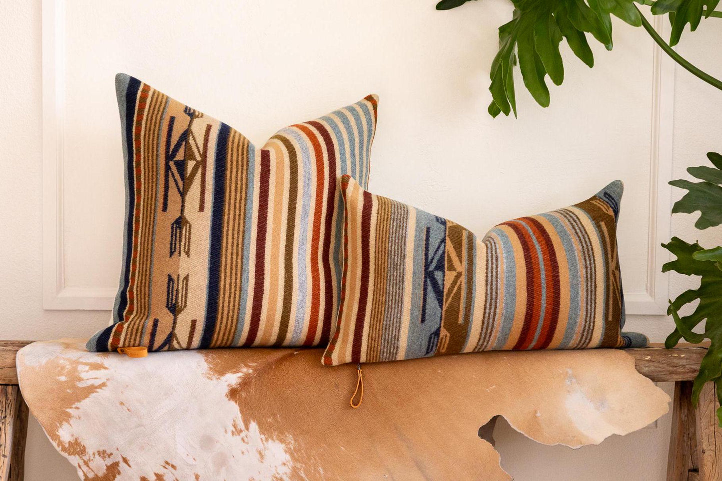 Decorative pillows with striped pattern on a wooden bench with cowhide texture.
