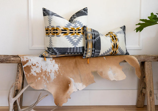 Decorative pillows with geometric patterns on a wooden bench with cowhide rug