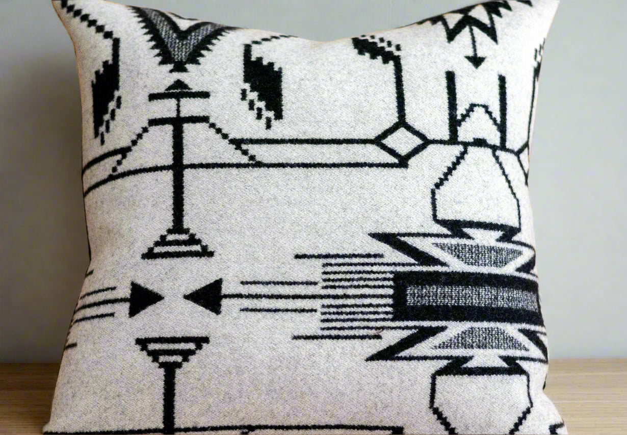 Decorative pillow with black geometric pattern on a wooden floor
