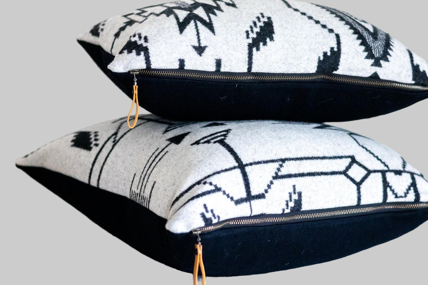 Two decorative pillows with geometric patterns stacked on a light surface.