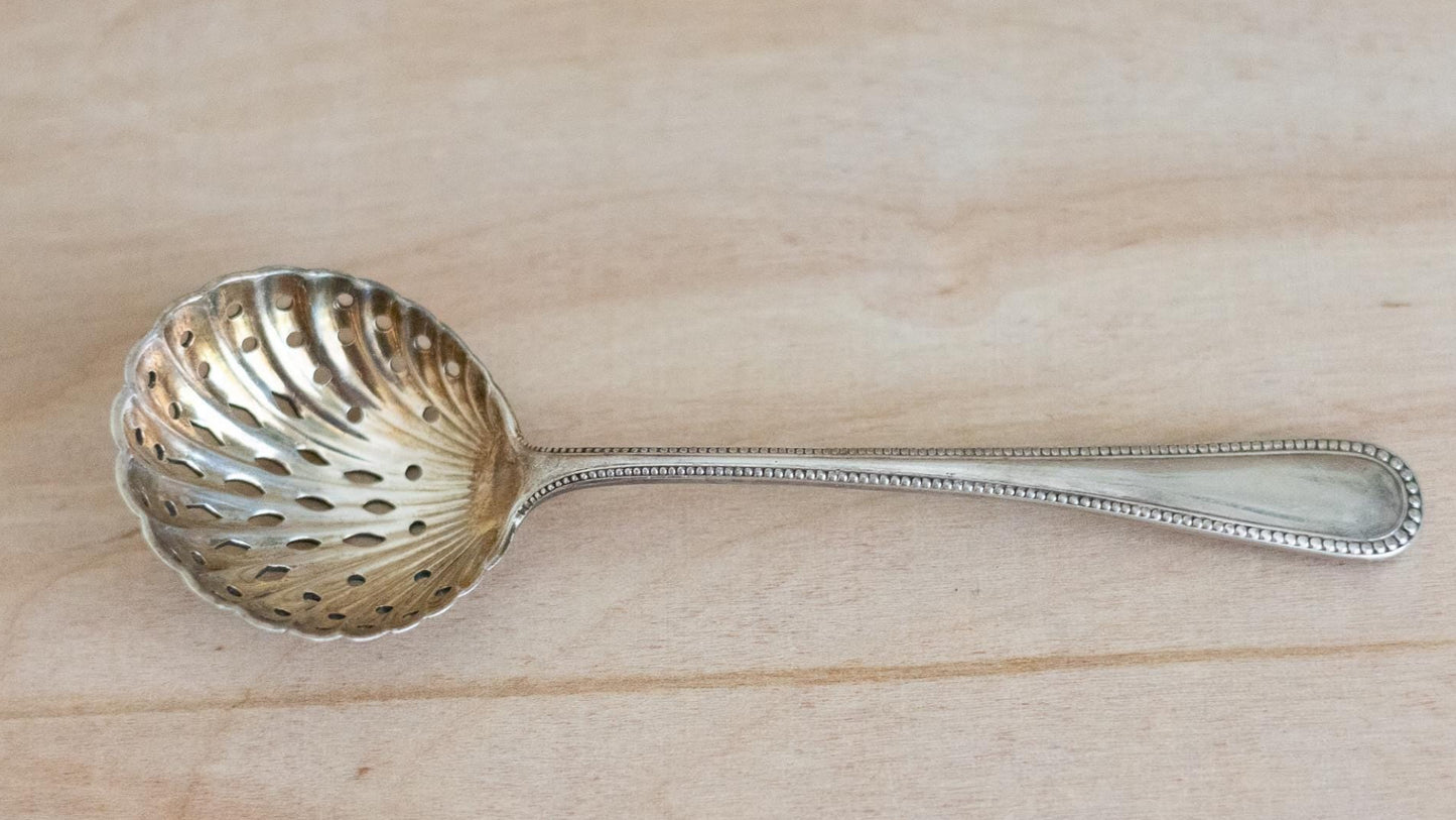 Silver sugar sifter decorative spoon on a wooden surface