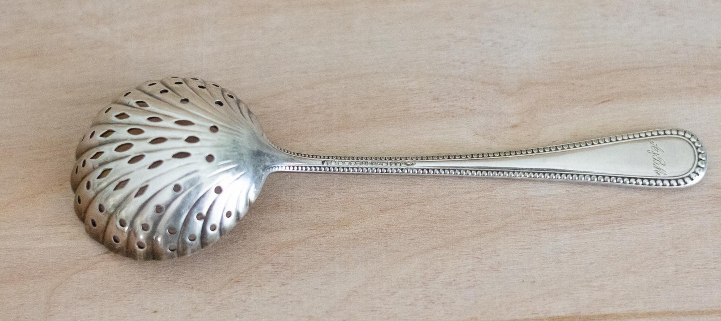 Silver sugar sifting spoon on a wooden surface
