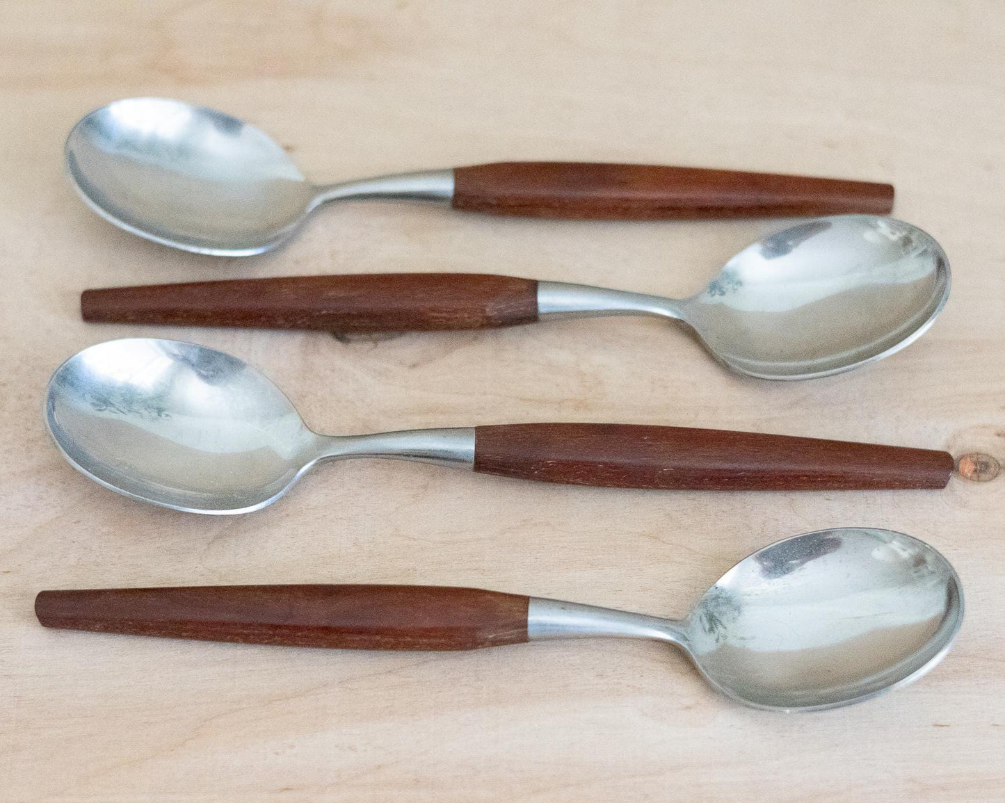 Four spoons with wooden handles on a light wood surface