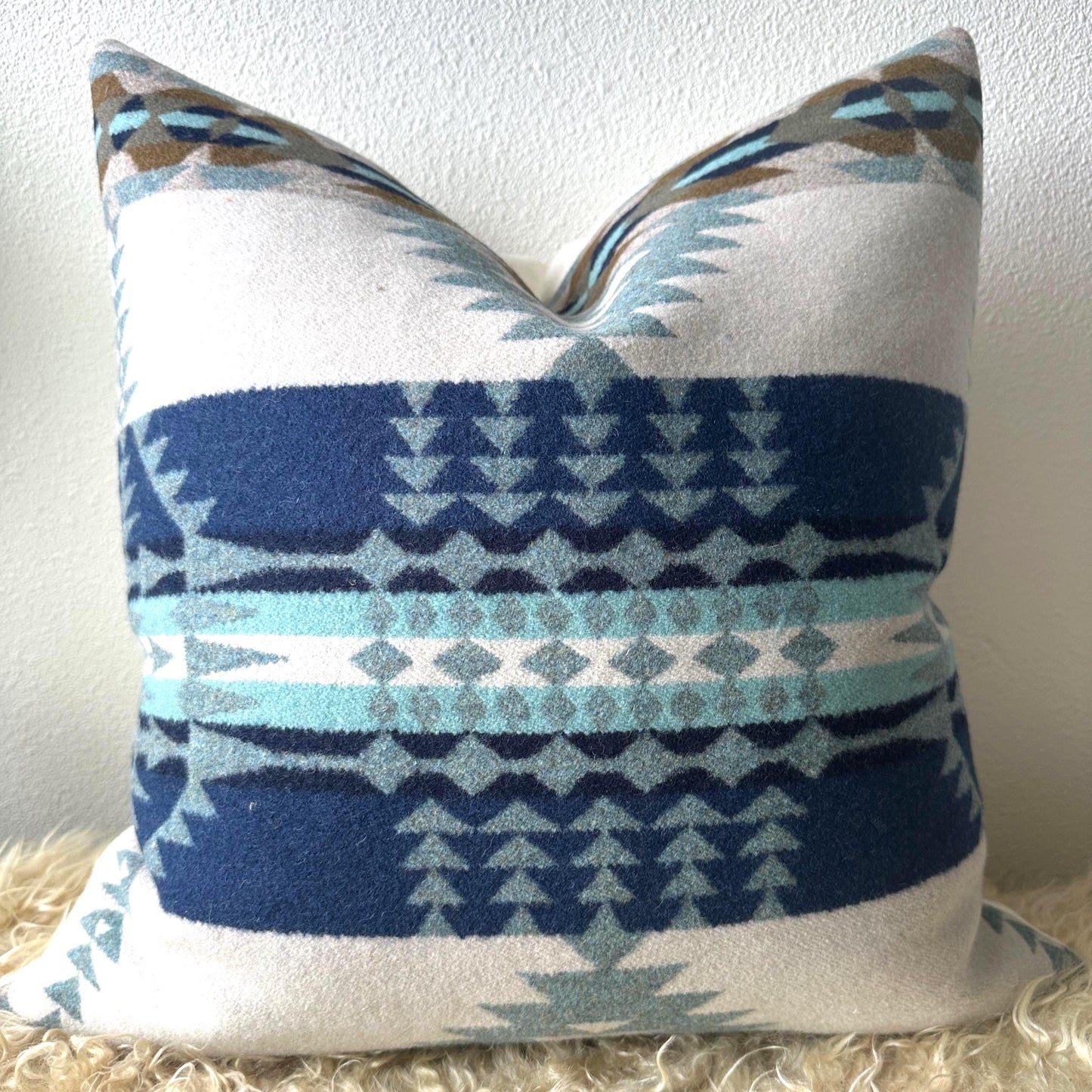 Decorative pillow with blue and white geometric pattern on a beige surface