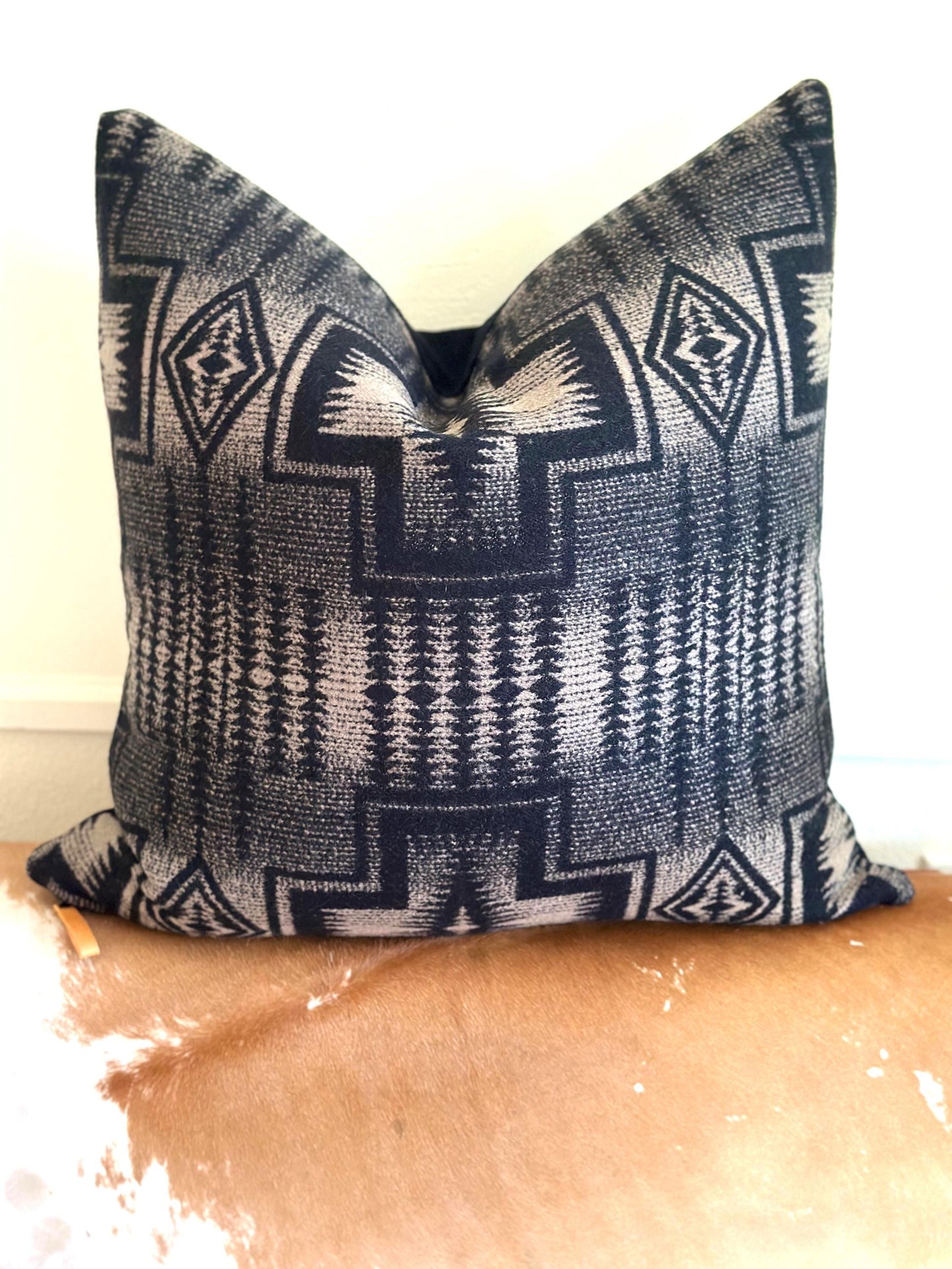 Decorative pillow with geometric pattern on a wooden surface