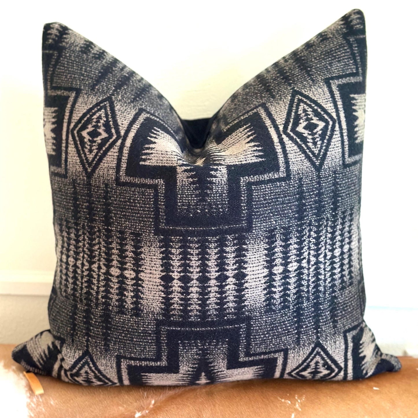 Decorative pillow with geometric pattern on a wooden surface