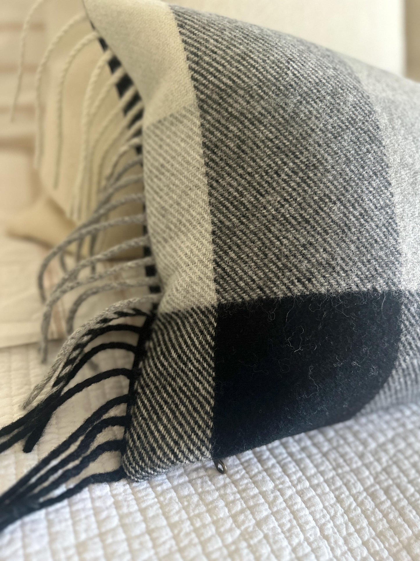 Plaid blanket with black and beige pattern draped over a surface