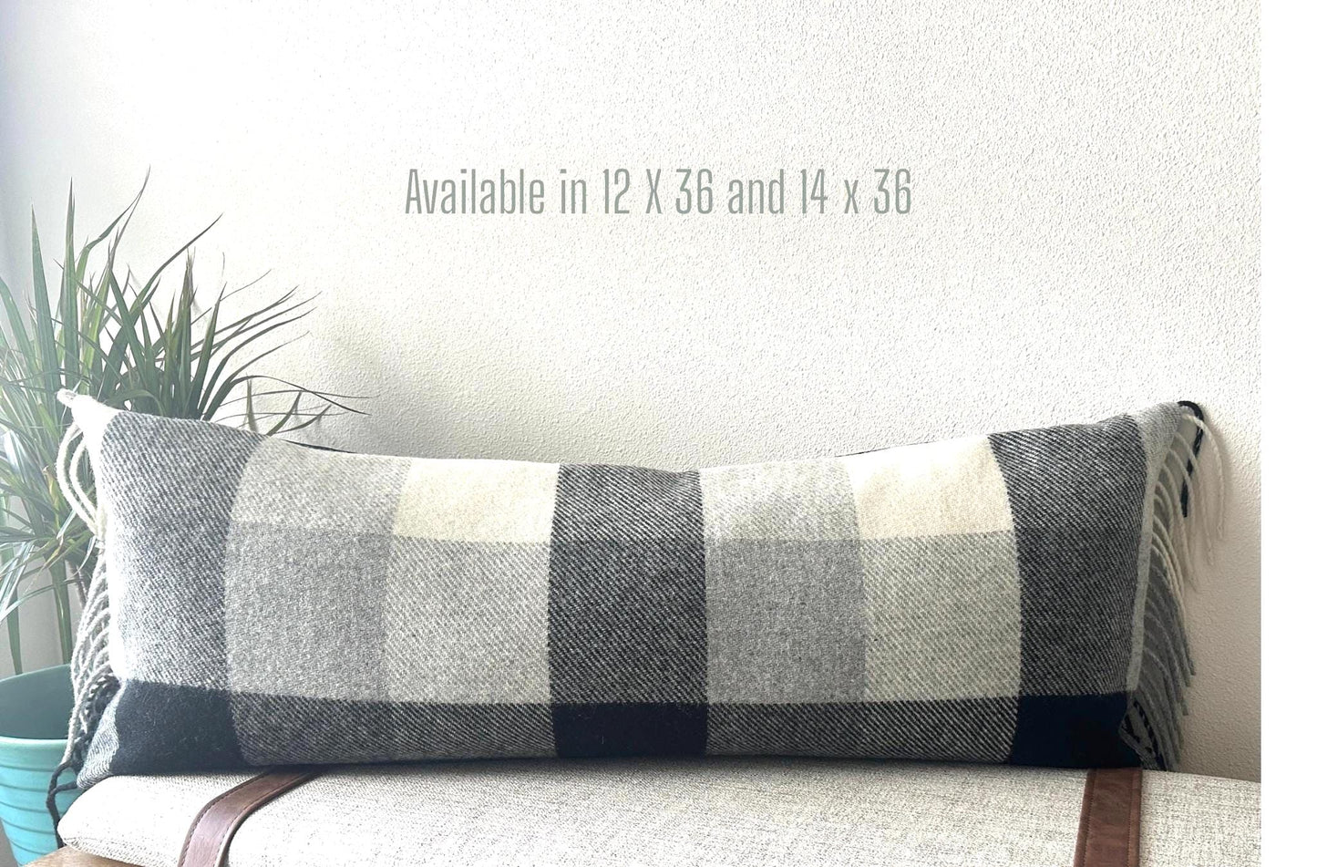 Plaid pillow on a couch with dimensions displayed 12 x 36 and 14 x 36